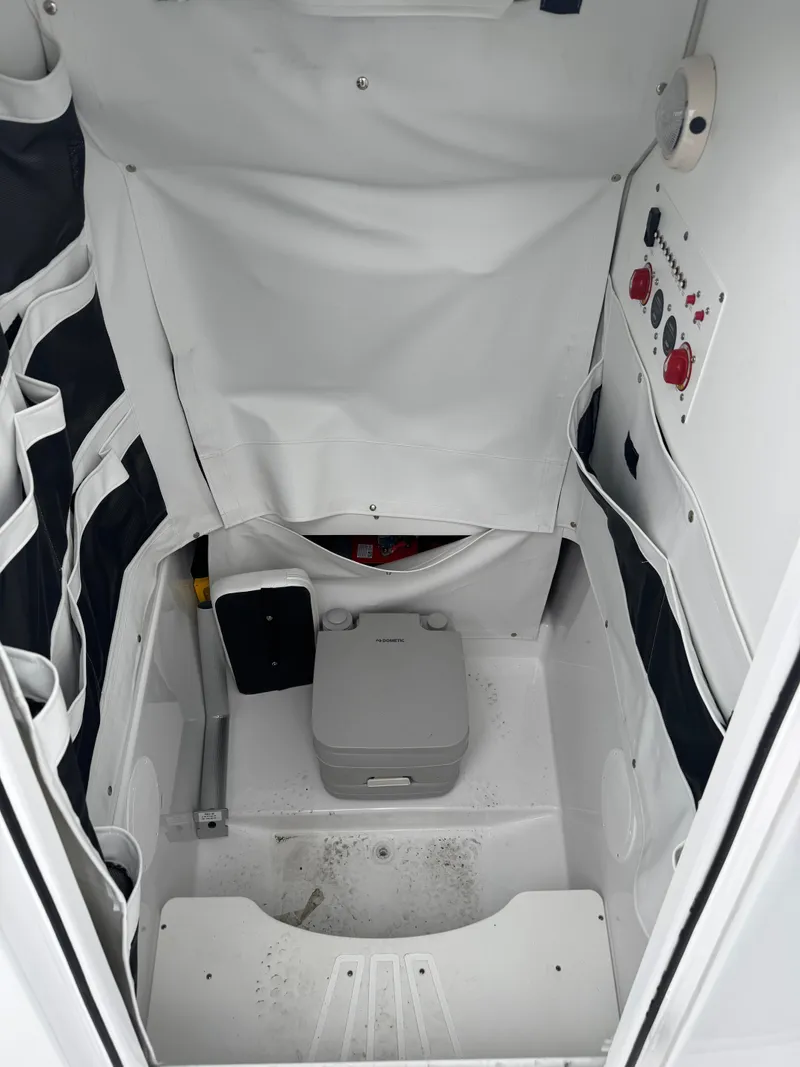 Slide: The Image of 2025 Wellcraft 263 Fisherman boat interior with compact marine toilet and storage compartments. - 29