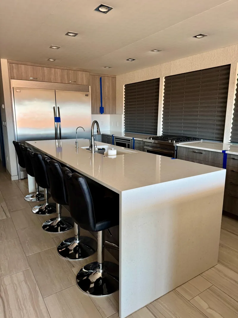 Slide: The Image of Modern kitchen with sleek island, bar stools, stainless steel appliances, and large windows. Adonia KSIX 2017. - 2