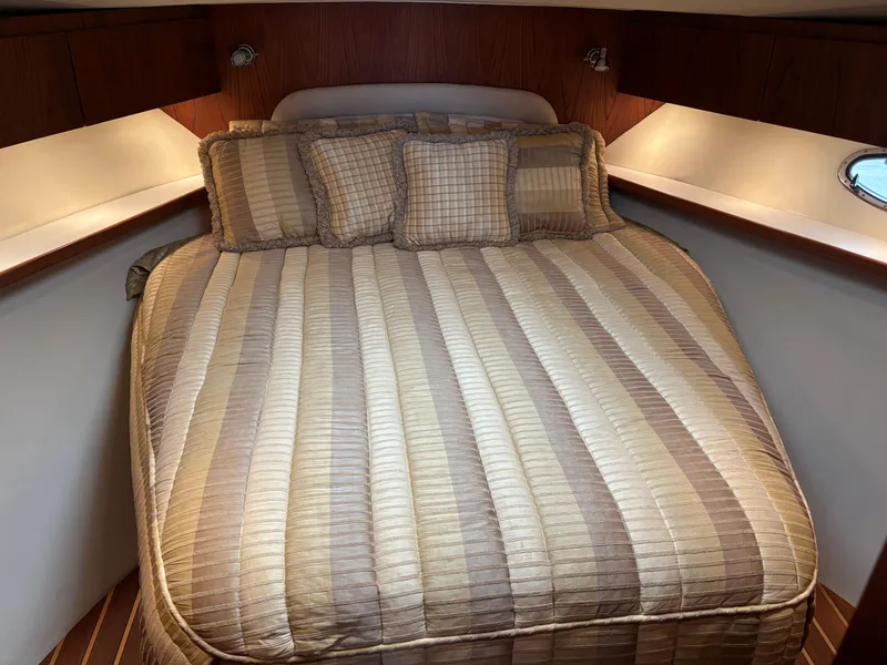 Slide: The Image of 2005 Tiara Yachts 3800 Open cabin with striped bedding and cozy lighting. - 62