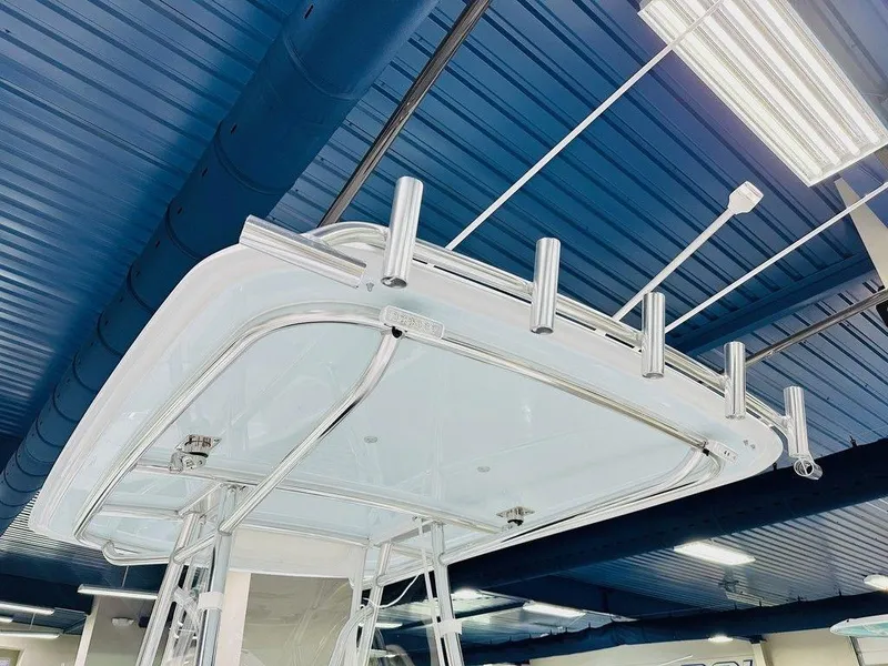 Slide: The Image of 2025 Contender 29BAY boat T-top with rod holders in a showroom. - 5