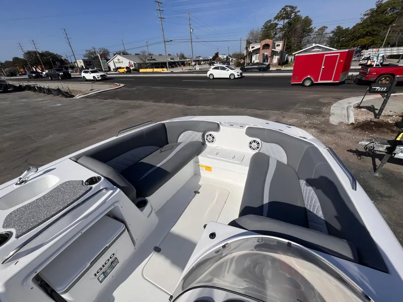 Slide: The Image of 2025 NauticStar 203 SC Deck boat interior with seating, parked near a road. - 10