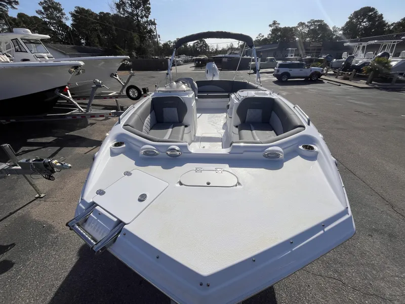 Slide: The Image of 2025 NauticStar 203 SC Deck boat, sleek design, spacious seating, parked outdoors. - 11