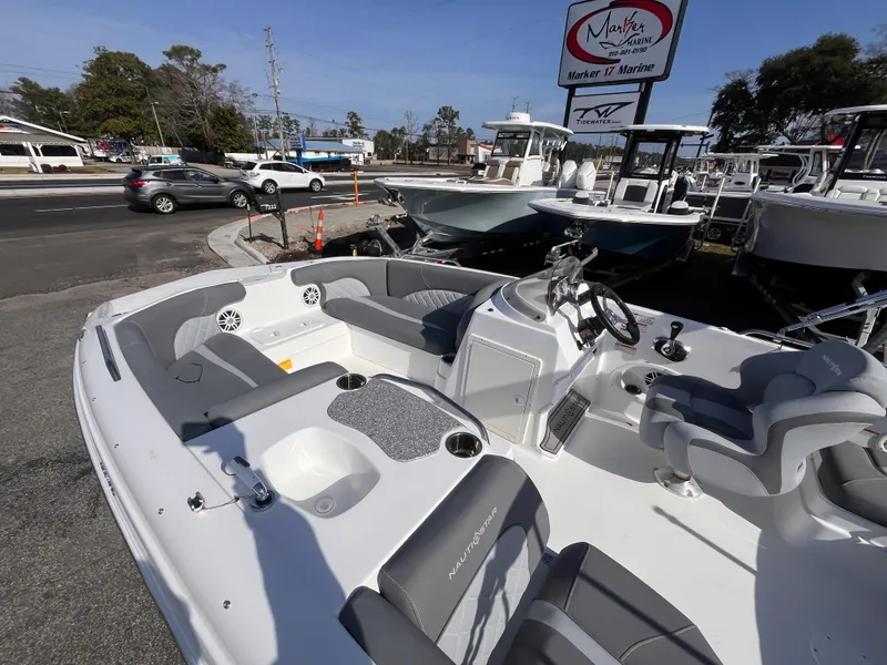 Slide: The Image of 2025 NauticStar 203 SC Deck boat displayed at a marina, showcasing seating and steering area. - 12