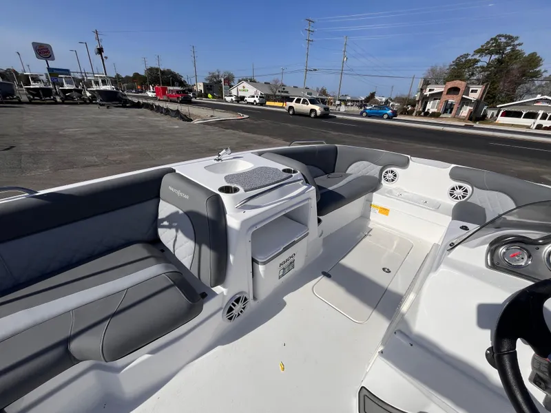 Slide: The Image of 2025 NauticStar 203 SC Deck boat interior with seating and storage, parked outdoors. - 9