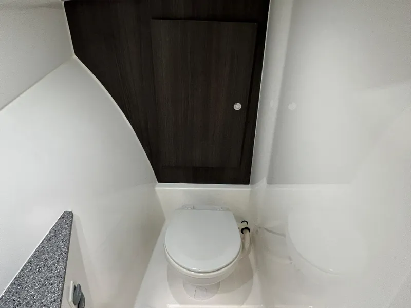 Slide: The Image of 2019 Albemarle 27 Dual Console boat interior bathroom with toilet and dark wood door. - 30