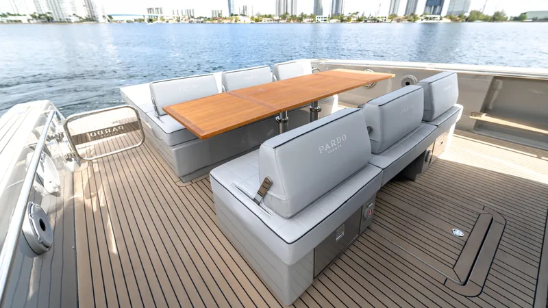 Slide: The Image of 2024 Pardo Yachts 43 deck with elegant seating and wooden table, overlooking serene waters. - 21