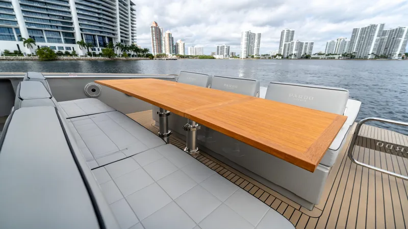 Slide: The Image of 2024 Pardo Yachts 43 deck with wooden table and gray seating, city skyline in background. - 25