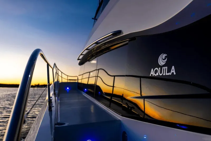 Slide: The Image of 2026 Aquila 50 Yacht at sunset, sleek design with illuminated deck. - 25