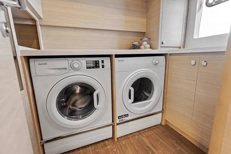 Slide: The Image of Laundry area with washer and dryer on 2026 Aquila 50 Yacht, featuring wooden cabinetry. - 46