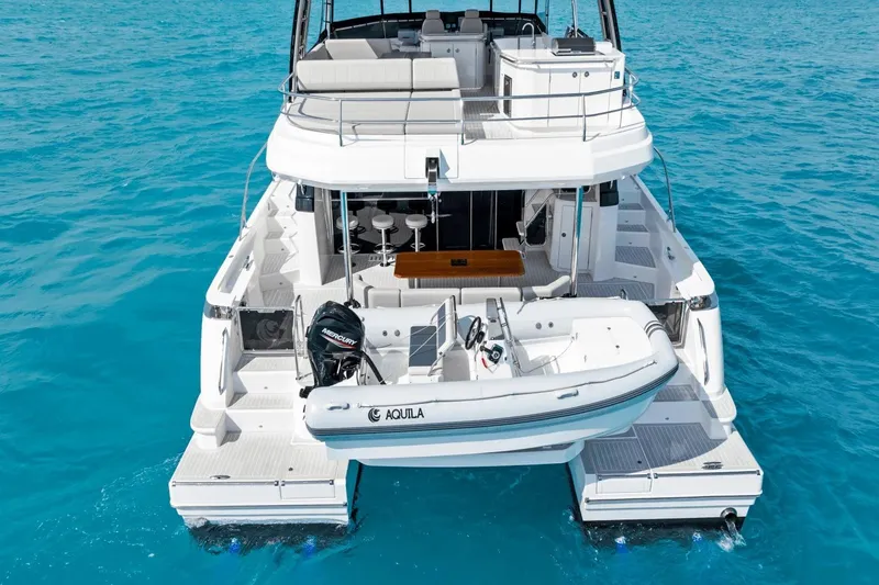 Slide: The Image of Aquila 50 Yacht 2026 on clear blue water, rear view with tender boat. - 7