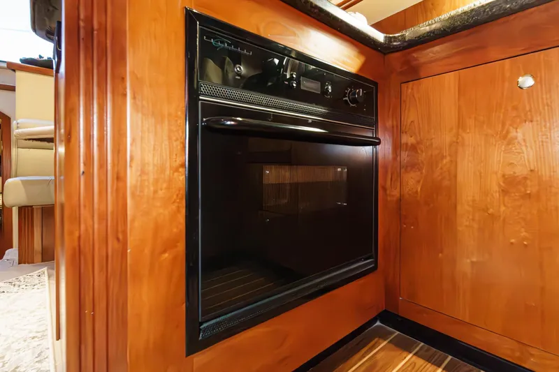 Slide: The Image of 2006 Cruisers 415 yacht kitchen with built-in black oven and wooden cabinetry. - 22