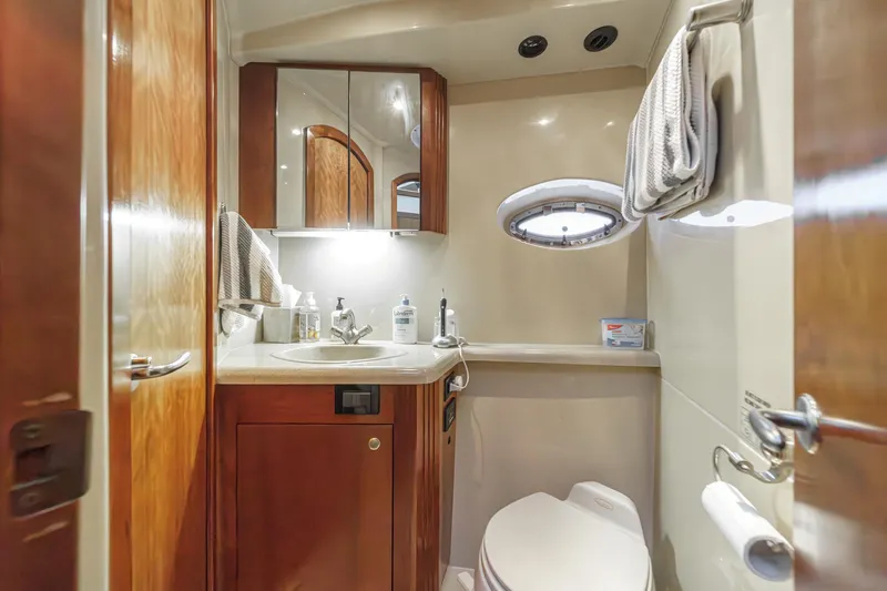 Slide: The Image of 2006 Cruisers 415 yacht bathroom with wooden cabinetry, sink, mirror, and porthole window. - 28
