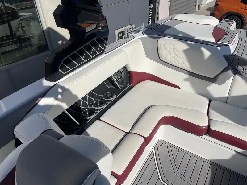 Slide: The Image of 2022 Nautique Super Air Nautique GS22 interior with white and maroon seating, cup holders, and modern design. - 9