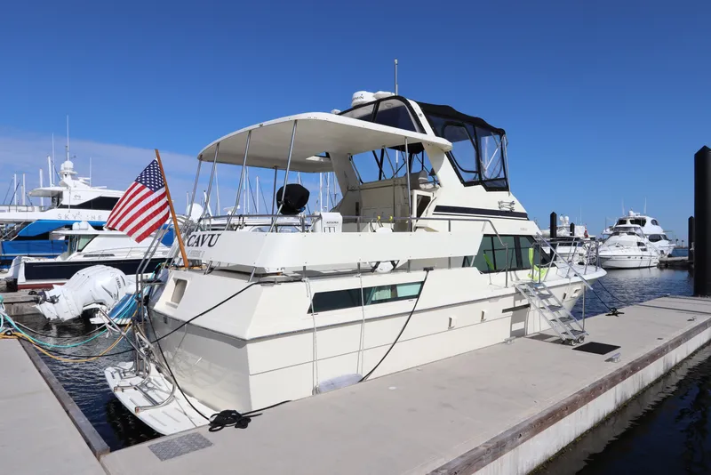 Slide: The Image of 1990 Hatteras 40 Double Cabin yacht docked at marina, featuring American flag and spacious deck. - 1