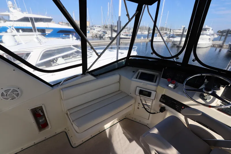 Slide: The Image of 1990 Hatteras 40 Double Cabin interior with marina view, featuring helm and seating area. - 18