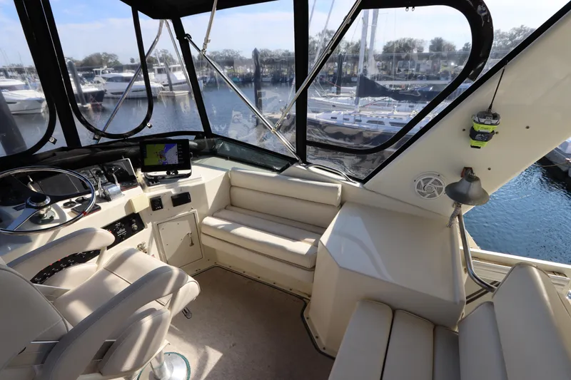 Slide: The Image of Interior view of 1990 Hatteras 40 Double Cabin yacht helm with marina backdrop. - 19