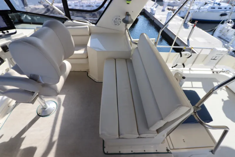 Slide: The Image of 1990 Hatteras 40 Double Cabin yacht interior with cushioned seating and helm view. - 20
