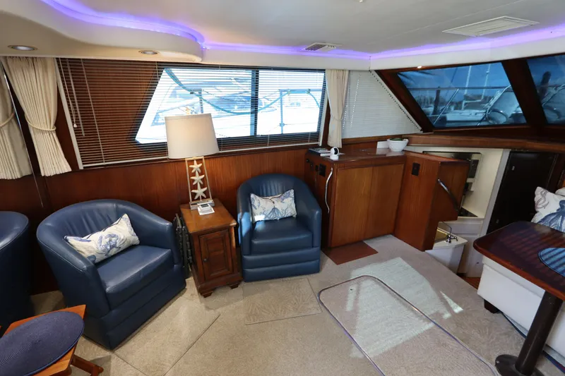 Slide: The Image of Interior of 1990 Hatteras 40 Double Cabin with blue chairs and wooden accents. - 32