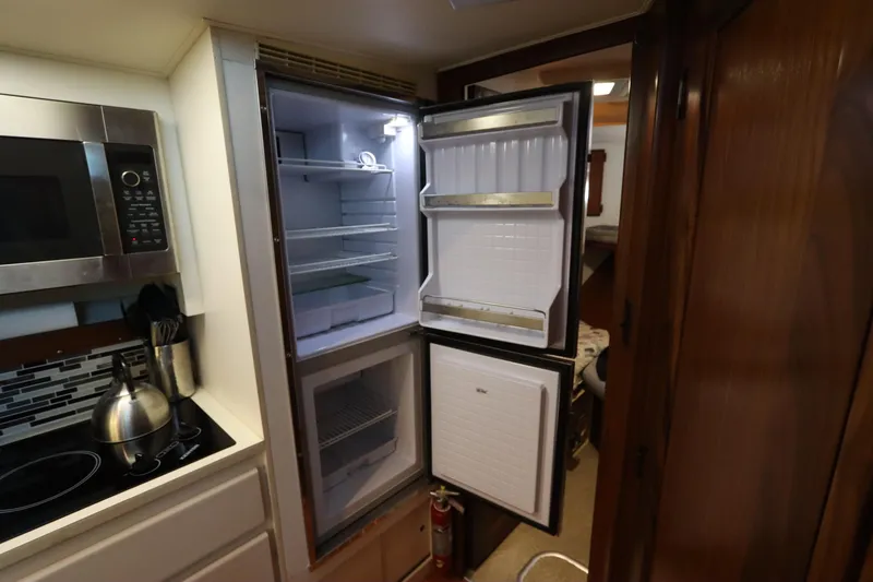 Slide: The Image of 1990 Hatteras 40 Double Cabin kitchen with open fridge, microwave, and kettle. - 41