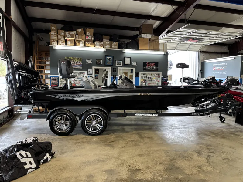 Slide: The Image of 2025 Ranger ALPHA 208 boat in showroom, black exterior, dual-axle trailer, indoor display. - 1