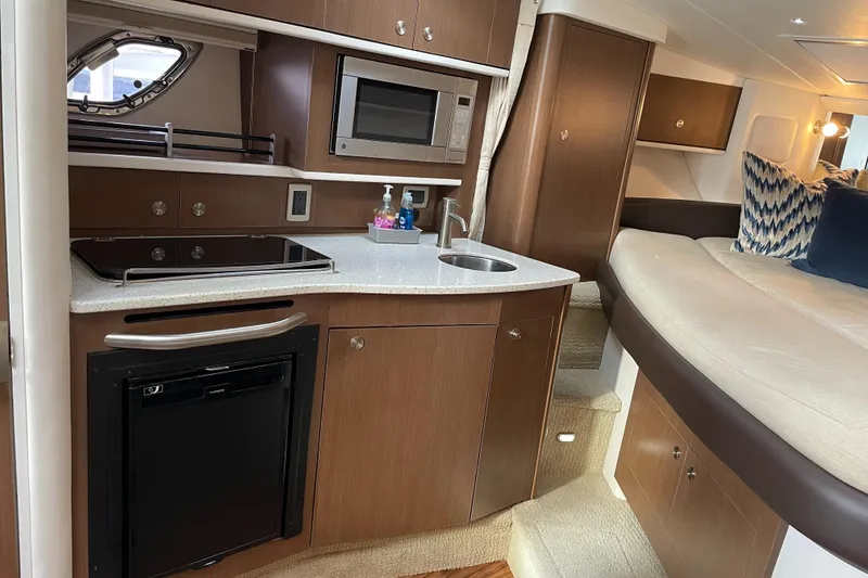 Slide: The Image of 2014 Sea Ray 330 Sundancer interior with kitchenette and seating area. - 12