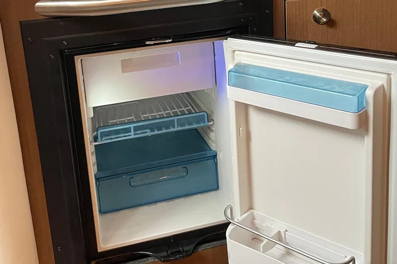 Slide: The Image of Open mini fridge inside 2014 Sea Ray 330 Sundancer boat, showing interior storage compartments. - 13