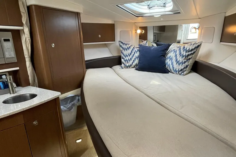 Slide: The Image of Interior cabin of 2014 Sea Ray 330 Sundancer with bed, pillows, and kitchenette. - 14