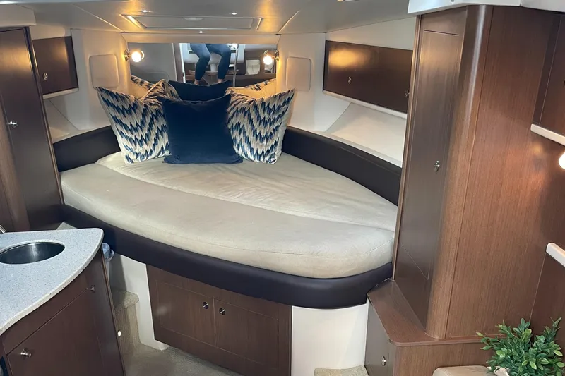 Slide: The Image of 2014 Sea Ray 330 Sundancer cabin with cozy bed and modern wood cabinetry. - 15