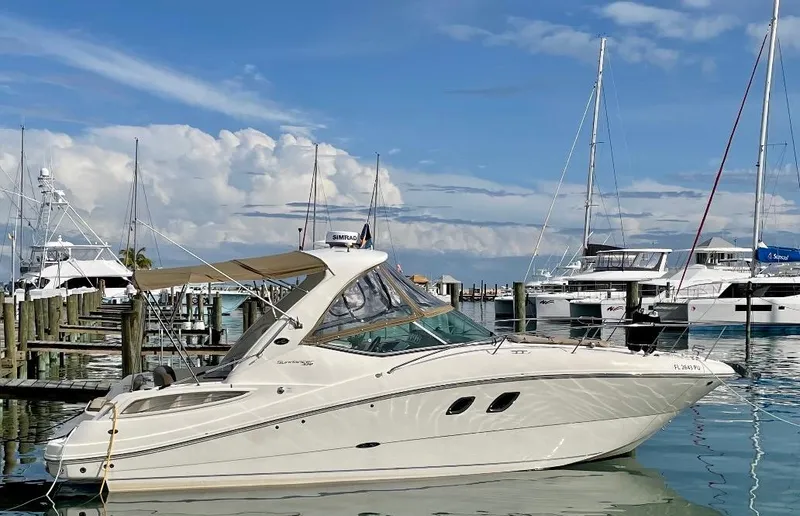 Slide: The Image of 2014 Sea Ray 330 Sundancer docked in a marina with sailboats and blue sky. - 27
