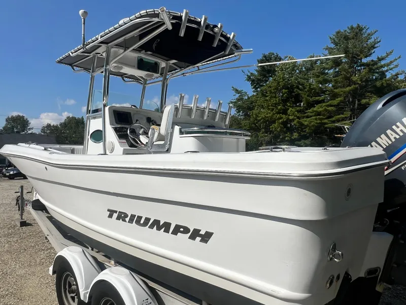 Slide: The Image of 2005 Triumph 23 Center Console boat on trailer, featuring a sleek white design and Yamaha engine. - 3