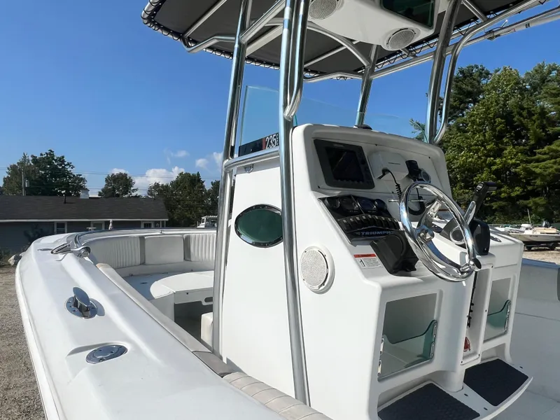 Slide: The Image of 2005 Triumph 23 Center Console boat with steering wheel and controls, docked outdoors. - 5