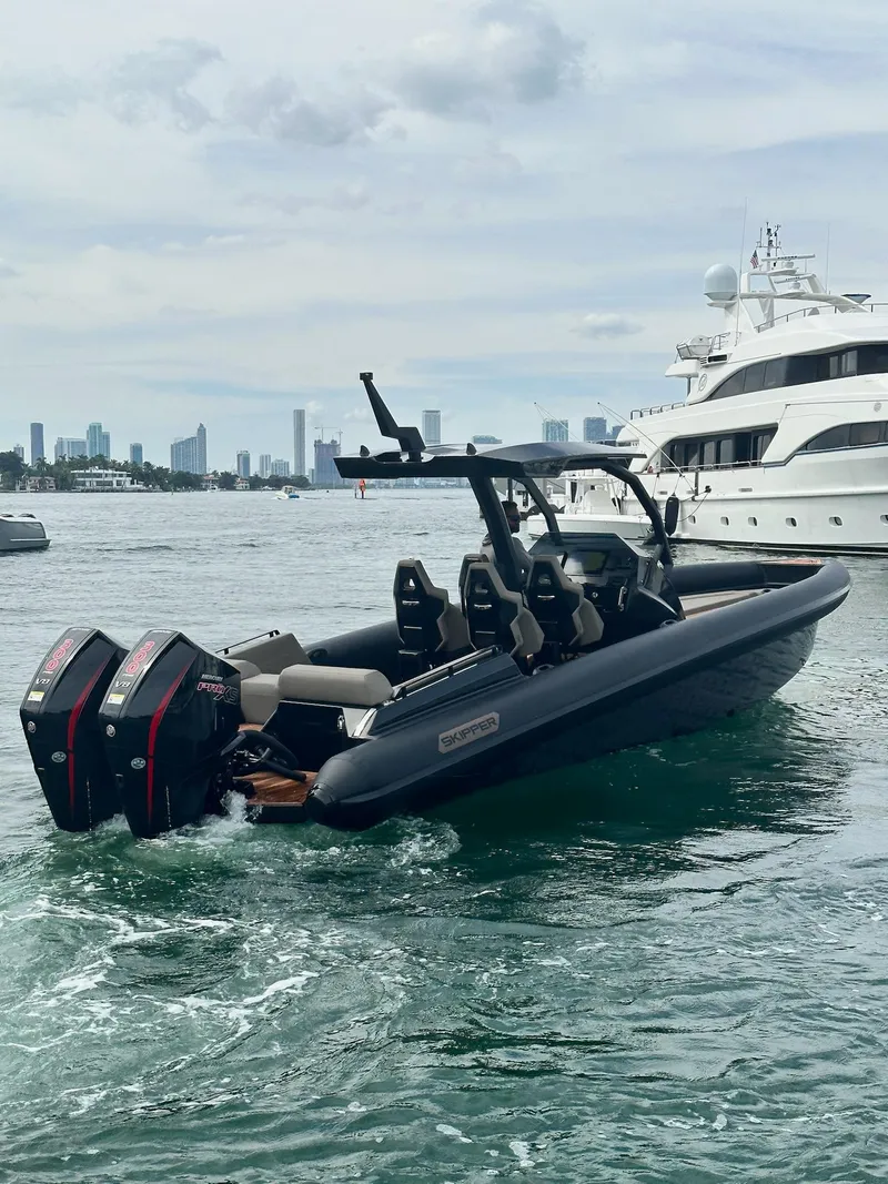 Slide: The Image of 2025 Skipper-BSK 34 boat with dual engines cruising near luxury yacht in city harbor. - 13