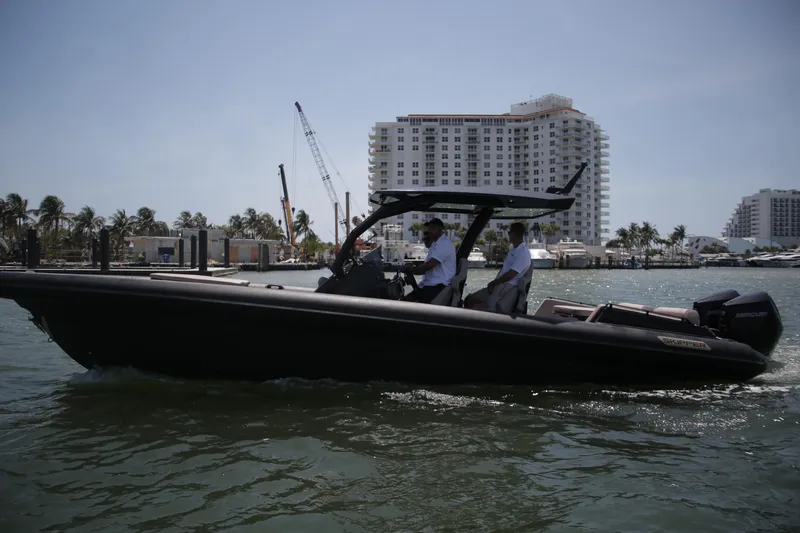 Slide: The Image of 2025 Skipper-BSK 34 boat cruising near waterfront buildings and palm trees. - 3