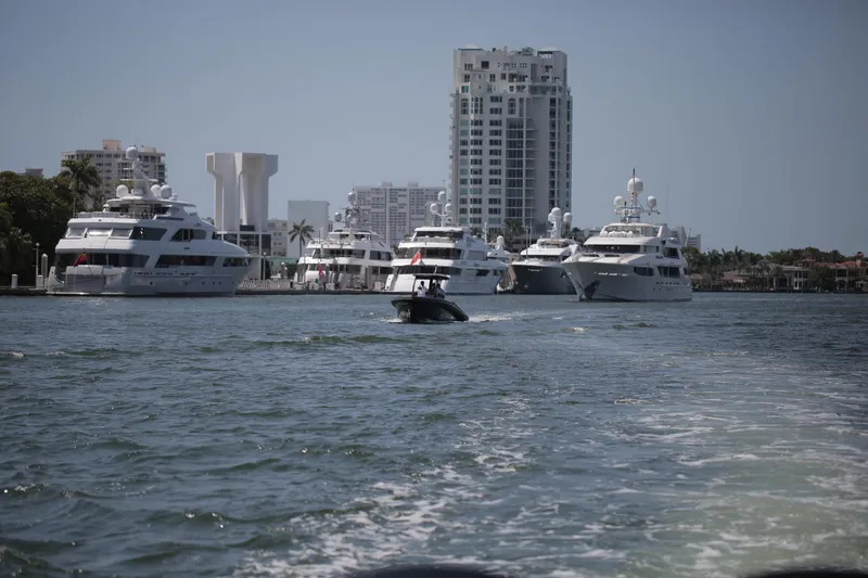 Slide: The Image of Skipper-BSK 34 boat cruising near luxury yachts and city skyline, 2025. - 5