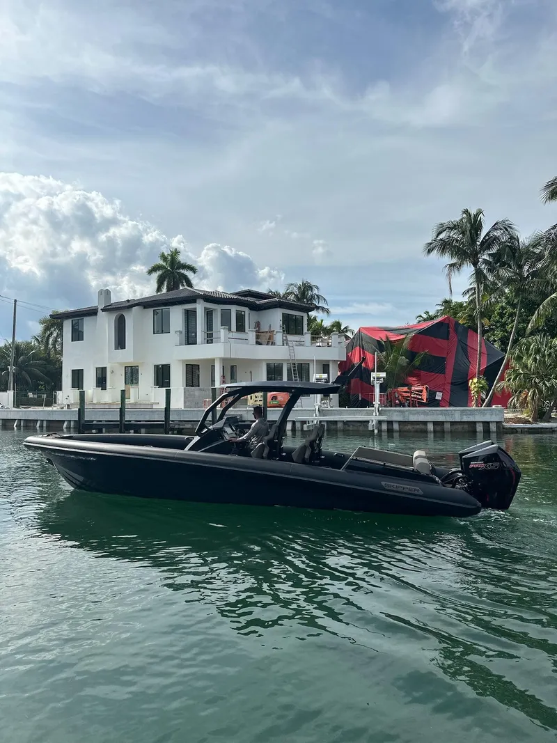 Slide: The Image of 2025 Skipper-BSK 34 boat on water near a modern waterfront house with palm trees. - 9