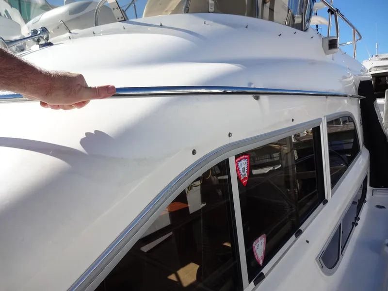 Slide: The Image of 1999 Sealine F44 yacht exterior with hand on chrome railing, showcasing sleek design and windows. - 17