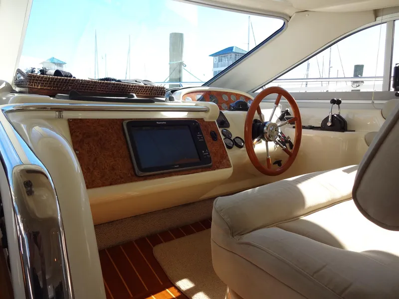 Slide: The Image of Interior of a 1999 Sealine F44 yacht, featuring a wooden steering wheel and navigation equipment. - 32