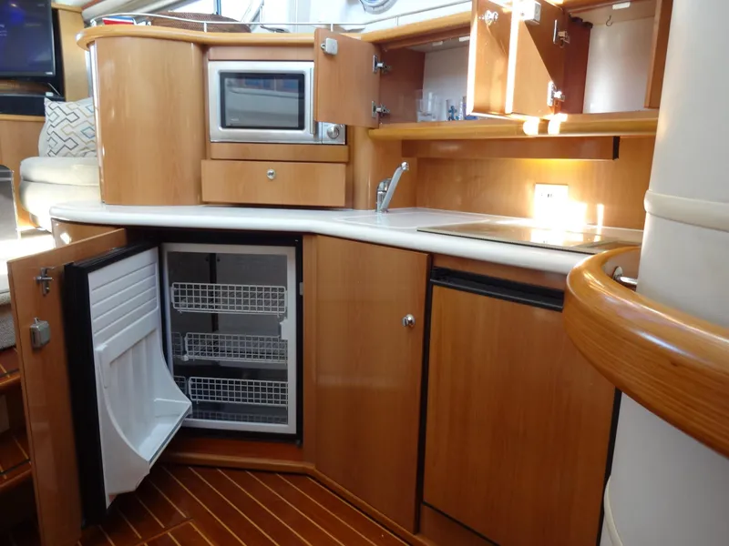 Slide: The Image of 1999 Sealine F44 yacht kitchen with wooden cabinets, microwave, sink, and open fridge. - 45