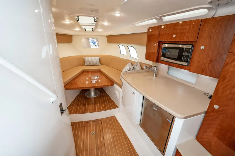 Slide: The Image of 2016 Intrepid 400 Cuddy interior with kitchenette, seating, and wood flooring. - 42
