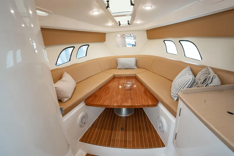Slide: The Image of 2016 Intrepid 400 Cuddy interior with beige seating and wooden table. - 43