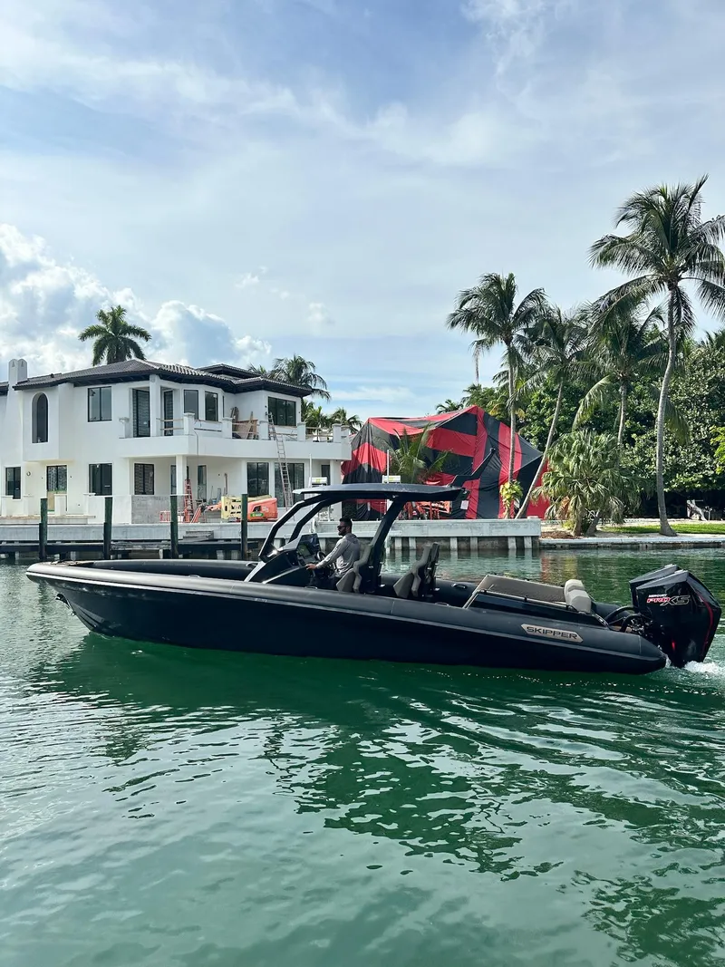 Slide: The Image of 2025 Skipper-BSK 34 boat cruising near waterfront homes and palm trees. - 10