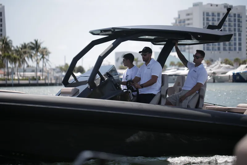 Slide: The Image of 2025 Skipper-BSK 34 boat with three people cruising near a marina, modern design, sunny day. - 2