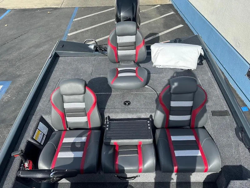 Slide: The Image of 2025 Ranger RT178 boat interior with gray and red seats, parked on pavement. - 13