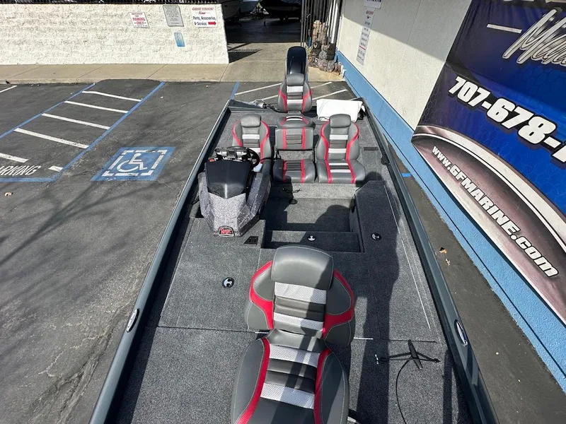 Slide: The Image of 2025 Ranger RT178 boat with gray and red seating, parked in a lot near a marine store. - 23
