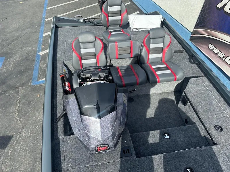 Slide: The Image of 2025 Ranger RT178 boat interior with gray and red seating, parked on pavement. - 24