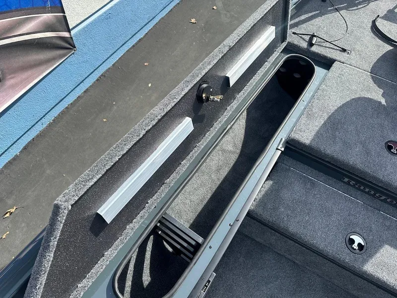 Slide: The Image of 2025 Ranger RT178 boat storage compartment with carpeted interior and secure locking mechanism. - 25
