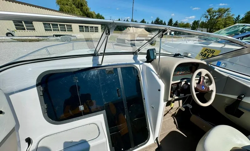 Slide: The Image of 1998 Four Winns Sundowner 205 boat interior with steering wheel and dashboard, for sale sign visible. - 4