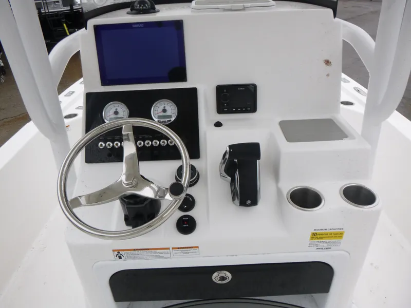 Slide: The Image of 2025 Sea Pro 250 Bay boat with dual seats and outboard motor, docked near covered boats. - 8