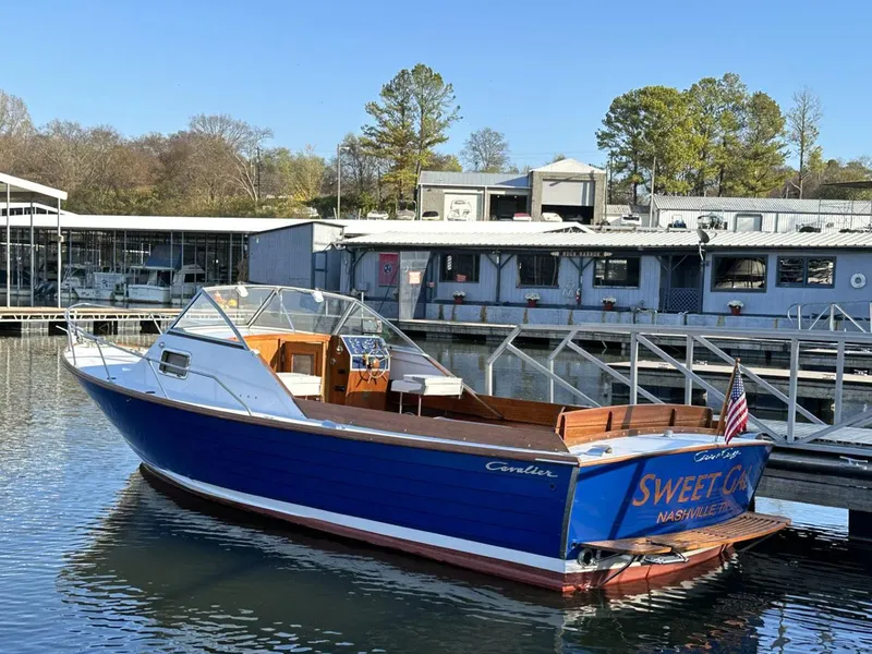 Slide: The Image of 1968 Chris-Craft Cavalier Cutlass 26 boat docked, blue hull, wooden interior, American flag displayed. - 1