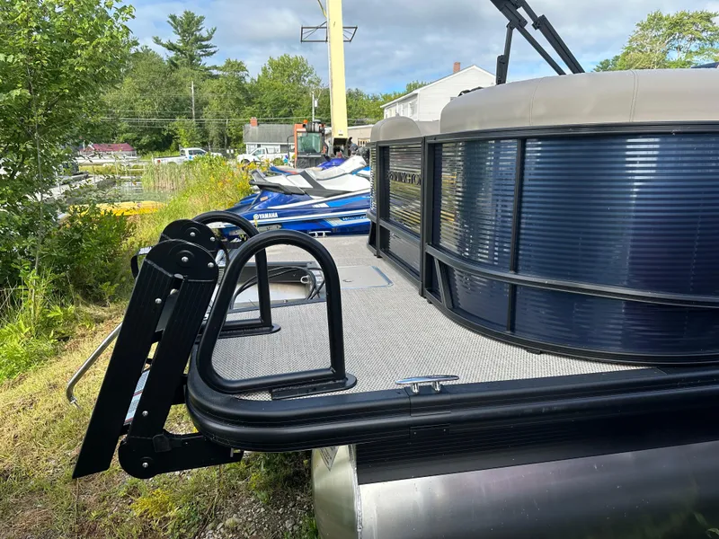 Slide: The Image of 2024 Bennington 22 SSR pontoon boat, side view, outdoors, with lush greenery background. - 10